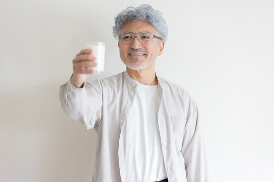 牛乳を手に笑顔を見せるシニア男性の健康的なライフスタイル
