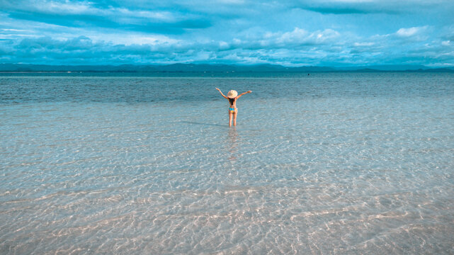 Woman tourist stay happy moment at the edge of the sea beach under shallow of the crystal clear water in summer trip on tropical island island