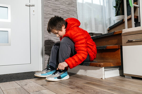 Boy tying shoelaces on stairs before leaving home