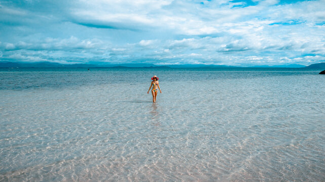 Woman tourist stay happy moment at the edge of the sea beach under shallow of the crystal clear water in summer trip on tropical island island