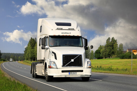 2004 Volvo VNL 64T 780 white semi-truck driving on the highway. 