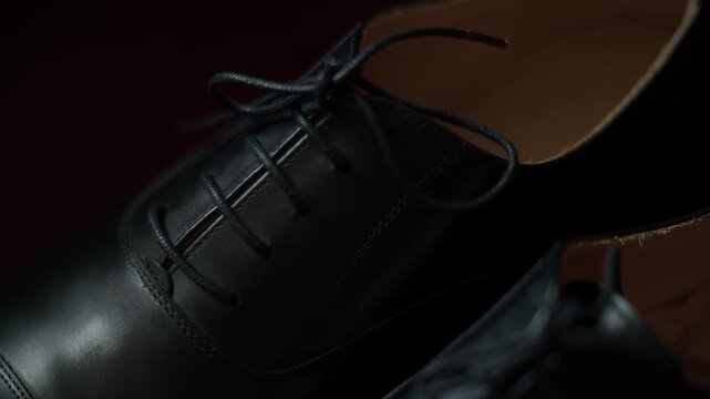 Black Leather Dress Shoes Close Up With Laces Stitching And Tan Leather Sole In Low Light