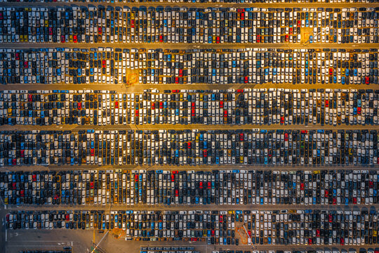 Aerial view of a vast car terminal filled with thousands of new vehicles parked in neat rows at the port of Civitavecchia, Lazio, Italy.