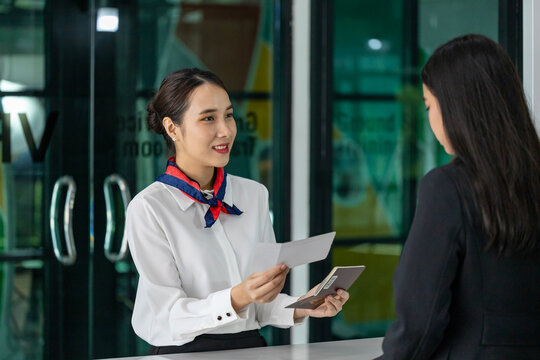 Asian business woman passenger is receiving boarding pass from the airline ground crew at check in counter at departure terminal into the airplane for final inspection before boarding to plane