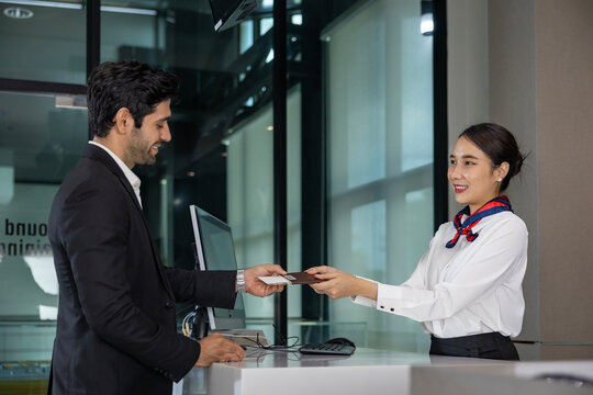 Caucasian businessman passenger is receiving boarding pass from the airline ground crew at check in counter at departure terminal into the airplane for final inspection before boarding to plane