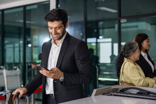 Caucasian businessman is using smart mobile phone while waiting in airline business departure lounge waiting for boarding to airplane