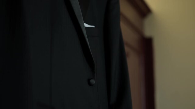 Groom Suit Jacket Detail With Satin Lapel Button And White Pocket Square In Warm Low Light
