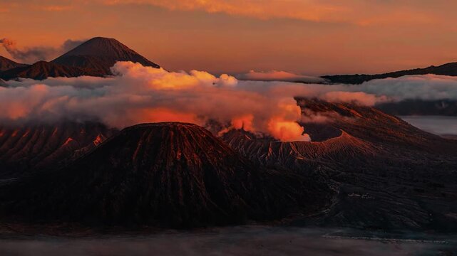 A breathtaking cinematic sunrise time-lapse and aerial perspective capturing the fiery morning light exploding across the majestic volcanic caldera and smoking cone of Mount Bromo in East Java.