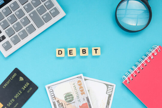 Top View of Financial Investigation Tools and Debt Letter Tiles on Blue Background