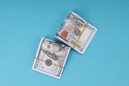 Top View of Dollar Banknote Bundles Tied with Rubber Bands on Blue Background