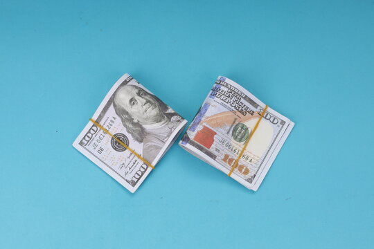 Flat Lay of Hundred Dollar Cash Stacks Isolated on Blue Background