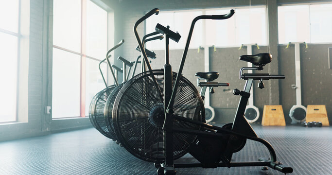 Empty, fitness and airbike in gym for cardio, wellness facility and setup for spin class with flare. Stationary bicycle, interior and equipment in training studio for cycling, development or machine