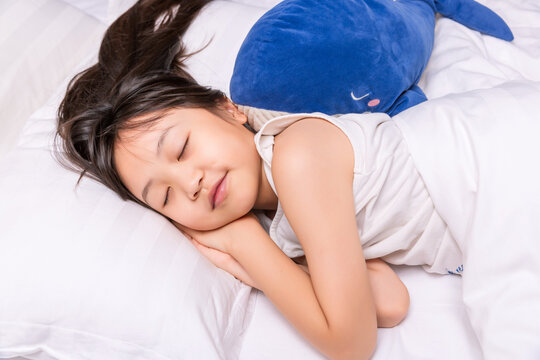 Asian little girl sleeping peacefully in bed, healthy sleep and childhood rest concept