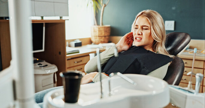 Woman, toothache or gum disease in dentist for cavity, oral infection or tooth extraction in clinic. Female person, patient or sore jaw with teeth ache or pain for root canal or dental treatment