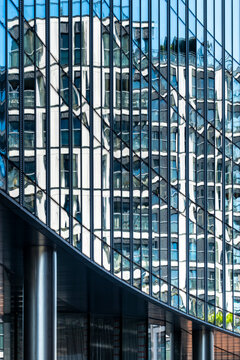 Curved glass high rise facade with reflections and vertical windows forming a dense geometric pattern across contemporary urban architecture and structural columns
