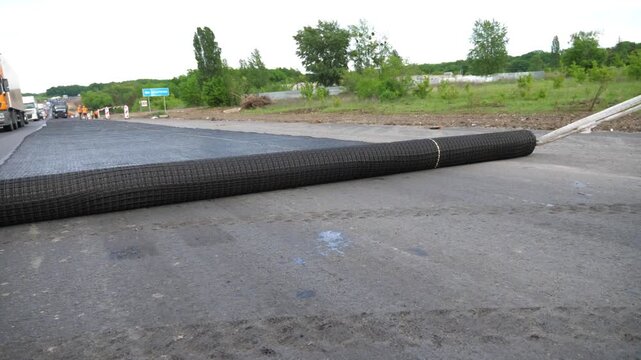 Workers prepare surface before laying a new layer of asphalt. Laying a protective layer before road work. Freeway repair industry. Highway construction process. Roadway renewal concept. Slow motion