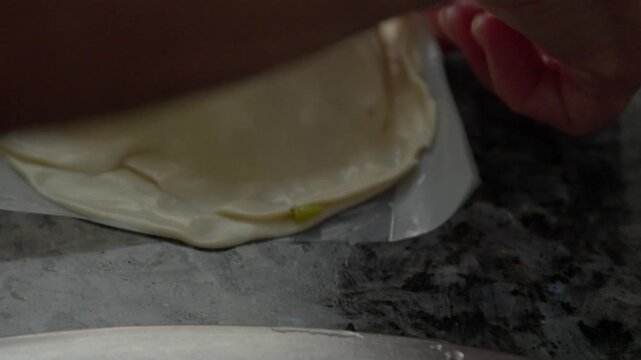Hands press and seal folded pastry dough while preparing a homemade Argentine empanada