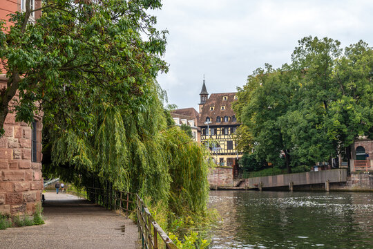 Tree-lined riverside path and historic buildings Strasbourg, France