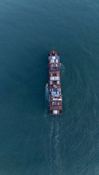 Aerial view of a large container ship carrying colorful cargo containers across the deep blue sea near the coast of Lagos, Lagos, Nigeria.