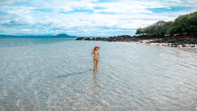 Woman tourist stay happy moment at the edge of the sea beach under shallow of the crystal clear water in summer trip on tropical island island