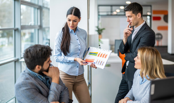 Businesswoman presenting financial charts and reports to her team during an office meeting