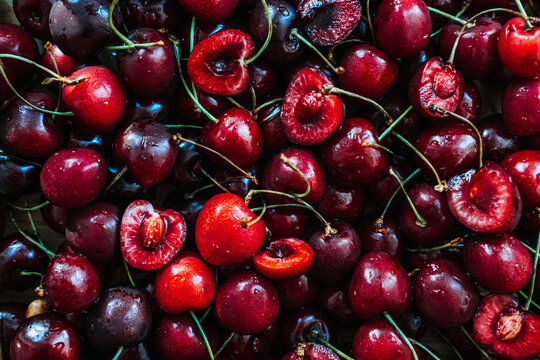 Close up background of fresh ripe sweet cherries with water droplets. Cooling summer food concepts, refreshing hot weather snacks, ice cold berry dessert, Hydrating summer fruits.