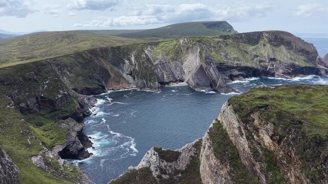 Cinematic aerial drone footage of the dramatic coastline near Eire 63 and Portacloy in County Mayo, Ireland. The drone flies around rugged cliffs, rocky headlands and a secluded Atlantic sea cove