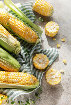 Fresh organic corn cobs and kernels on rustic background