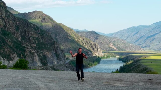High quality static footage of an energetic man running into frame and performing expressive martial arts movements against the stunning backdrop of the Kur-Kechu valley and Katun River in Altai, Sibe