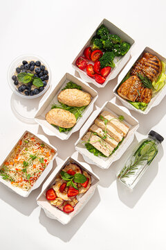 Complete balanced daily meal prep menu with meat fish vegetables oatmeal and detox water in craft containers on white background