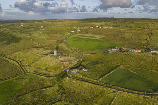 Aerial view of Doonagore Castle surrounded by green fields, winding roads, and rural landscape in Doolin, County Clare, Ireland.