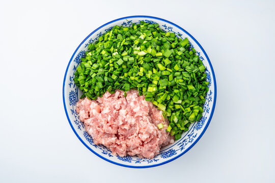 A bowl of chive and pork dumpling filling on a white background.