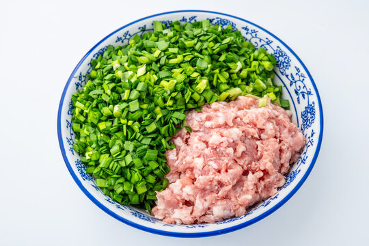 A bowl of chive and pork dumpling filling on a white background.