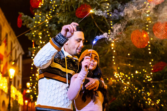 Young couple enjoying sparklers during christmas eve celebration outdoors