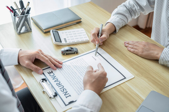 Car dealer manager presenting customer signing car document cont