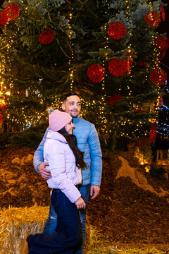 Couple embracing near a large christmas tree celebrating holiday season at night