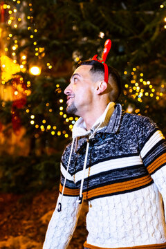 Young man enjoying festive christmas lights wearing reindeer headband