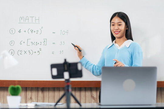 Female tutor standing in front of whiteboard and writing math eq