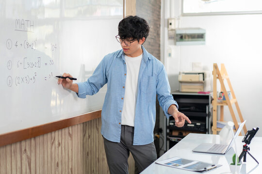 Male tutor standing in front of whiteboard and writing math equa