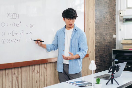Male tutor standing in front of whiteboard and writing math equa