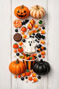Halloween candy arrangement with pumpkins ghost sweets and festive treats on white wood