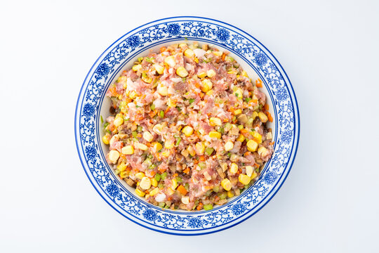 A bowl of pork dumpling filling with corn, vegetables, and mushrooms.