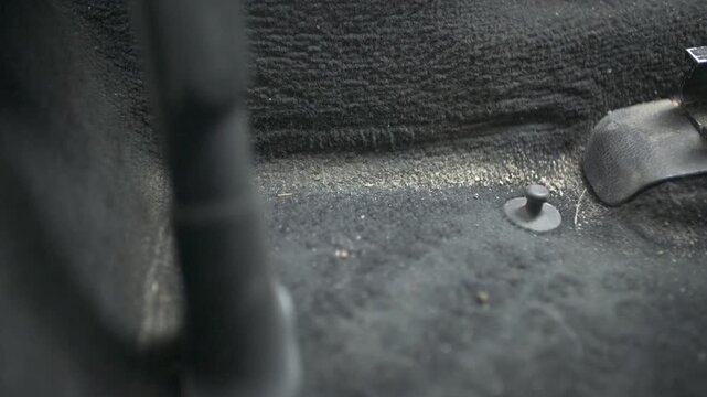 Vacuuming dirty car carpet during professional interior detailing process with powerful suction tool.