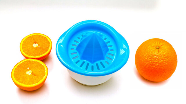 Cut and whole orange citrus fruit next to a plastic juicer sieve tool on kitchen counter