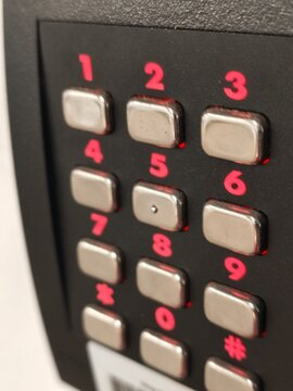 A close-up shot of a metallic keypad pin pad with metallic silver buttons and pink numbers on an electronic terminal device.