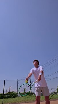 晴天のクレーコートで4kスローモーション撮影されたテニス選手の迫力あるサーブ前進フォーム