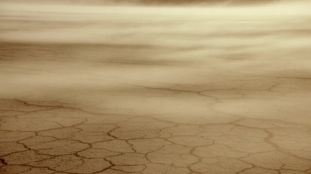 Cracked dry earth stretches across a hazy barren landscape under dusty light