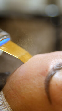 Professional beautician applying cleansing mask on female client's face. Mesotherapy. Close-up of female face during youth restoration and facial rejuvenation procedure.
