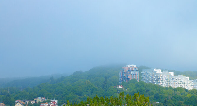Misty morning view of residential buildings green hills on city outskirts apartment complex a serene atmosphere on the edge of town