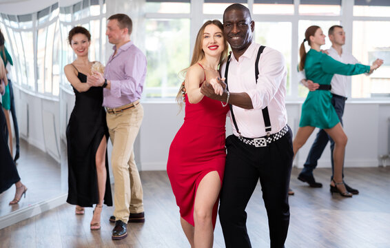 Dance studio - a group of beautifully dressed people learn to dance tango